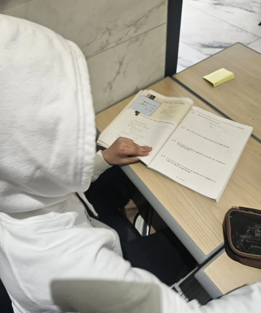 한 학생이 책상에 앉아 교재 문제를 혼자 푸는 모습